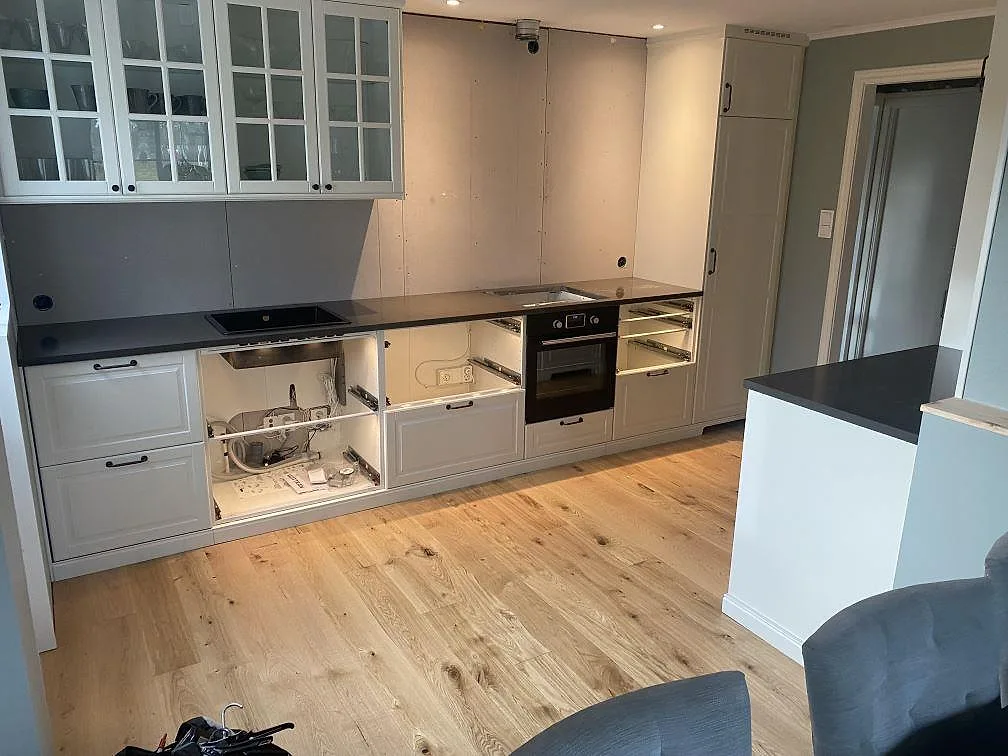 Køkkenbordplader i mørk Silestone Calypso, poleret komposit, monterade på vita köksstommar i ett køkken i Brålanda.