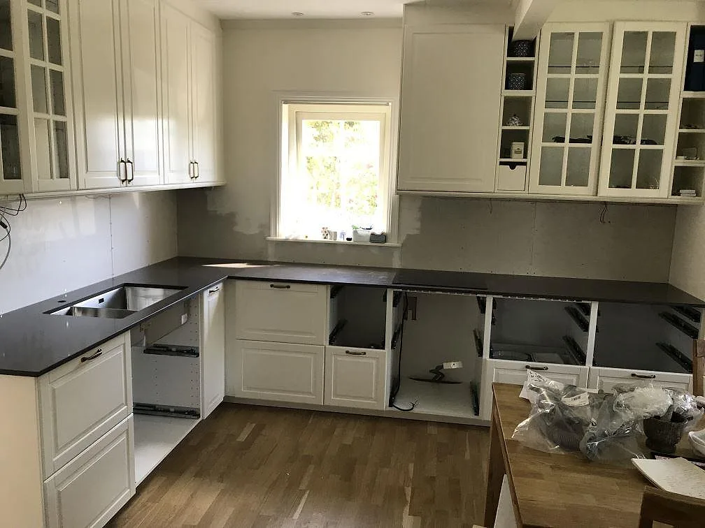 Køkkenbordplade i mørk Silestone Calypso, poleret kvartskomposit, monteret rundt om ett U-format køkken med underlimmad vask og induktionshäll under montering i Mölndal.