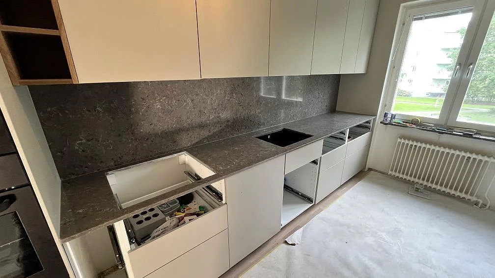 Køkkenbordplade i poleret Silestone Copper Mist komposit med matchande stænkplade og synliga udskæring i ett køkken i Norrköping.