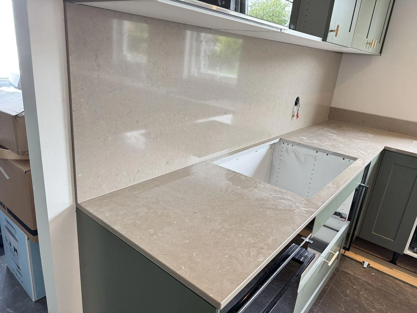 Køkkenbordplade og vægbeklædning i poleret Silestone Coral Clay, kvartskomposit, med öppen diskhozon i ett køkken i Bara.