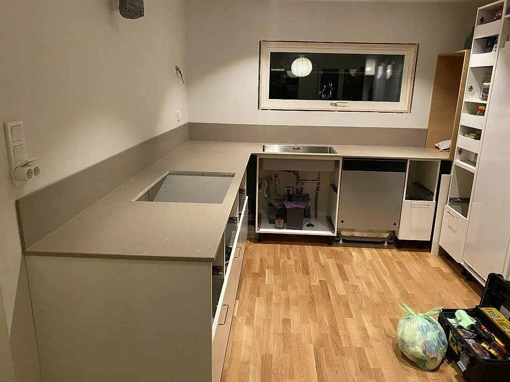 Køkkenbordplade i mat Silestone Coral Clay med uppvikt stænkplade og öppna köksstommar under montering i Billdal.