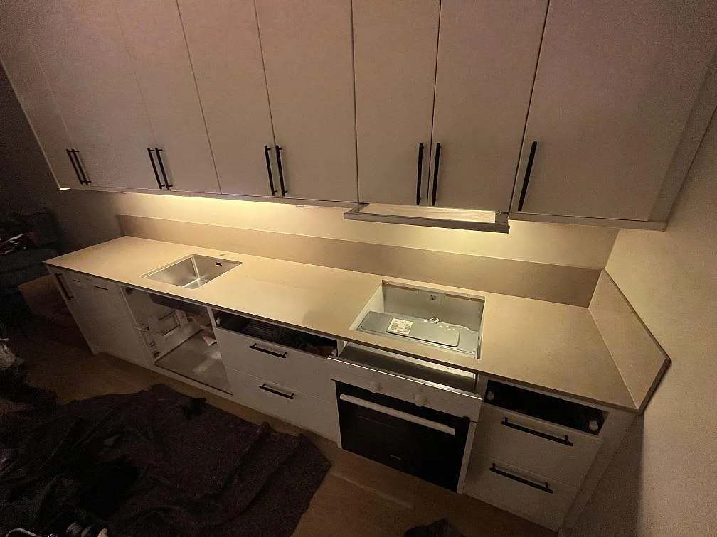 Køkkenbordplade i grå Silestone Coral Clay, poleret komposit, med stänkkant samt öppningar for vask og kogeplade i ett køkken i Bromma.