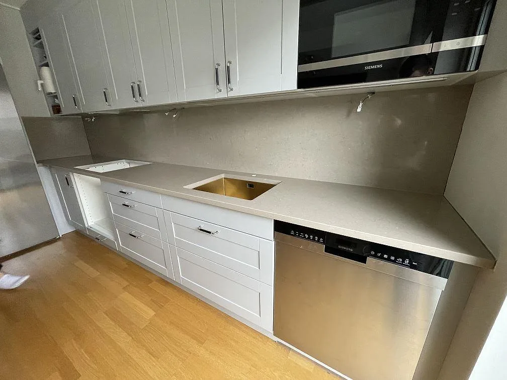 Køkkenbordplade i Silestone Coral Clay, poleret komposit, med synlig vask, hällöppning og stænkplade i ett køkken i Enköping.