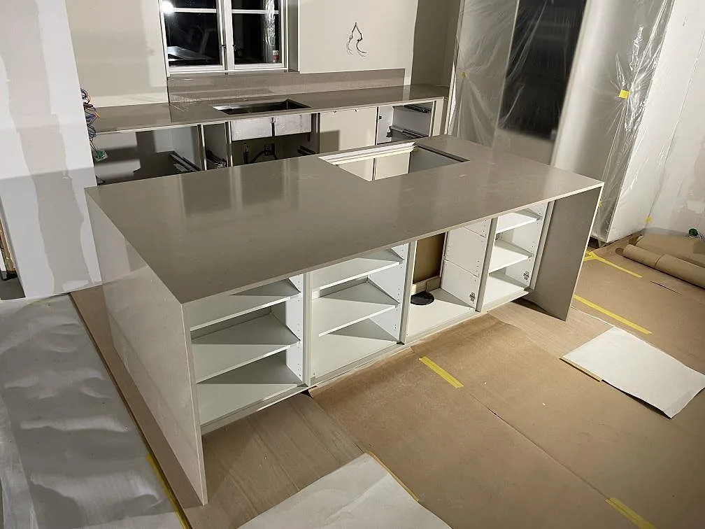 Køkkenø og väggbänkskiva i varm gråbeige Silestone Coral Clay, poleret kvartskomposit, monteret i ett køkken under montering i Falun.