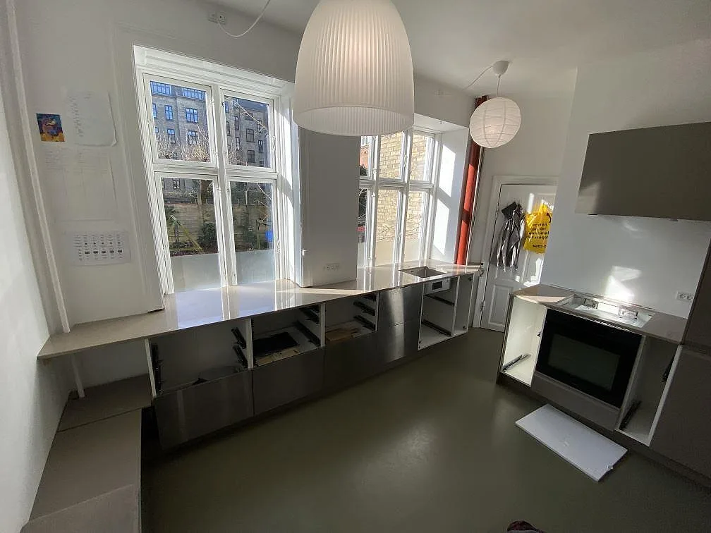 Køkkenbordplade i poleret Silestone Coral Clay, komposit, monteret längs fönstren i ett køkken i Frederiksberg c.