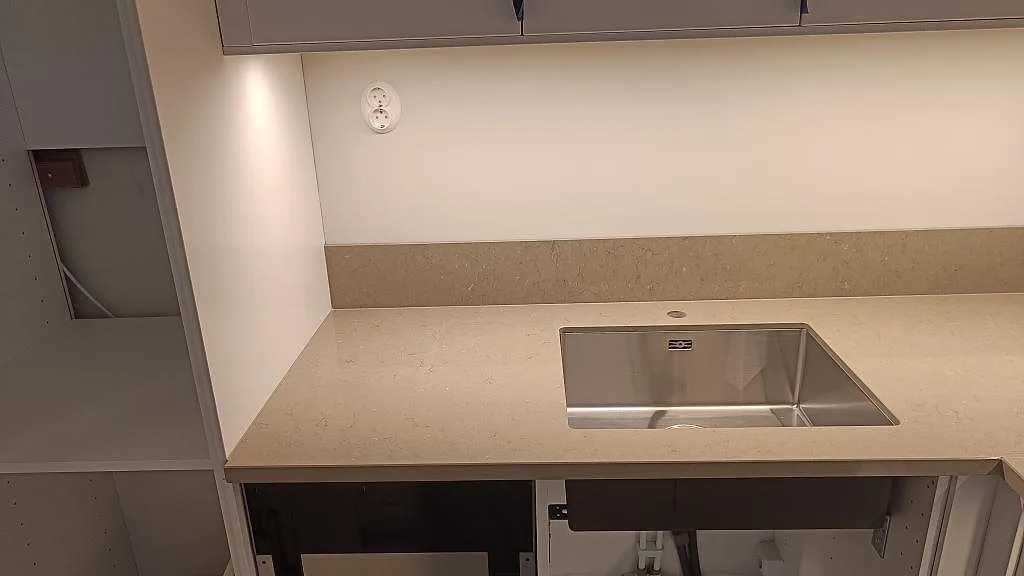 Køkkenbordplade i Silestone Coral Clay, poleret kvartskomposit, med låg stänkkant og rostfri vask i ett køkken i Göteborg.