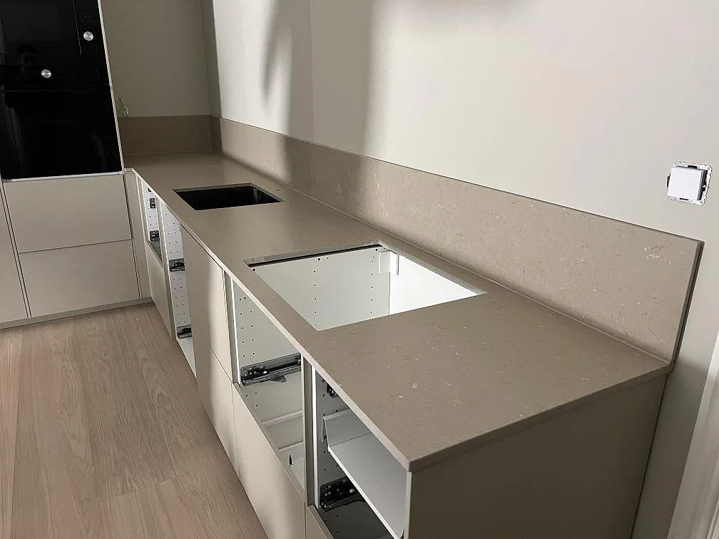 Køkkenbordplade i gråbeige komposit, Silestone Coral Clay i mat Mocka, med stænkplade og synliga udskæring under montering i Hägersten.