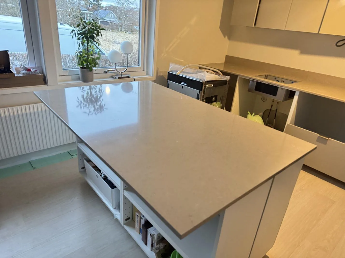 Køkkenø og køkkenbordplade i poleret Silestone Coral Clay, varm greige komposit, i ett køkken under montering i Länghem.