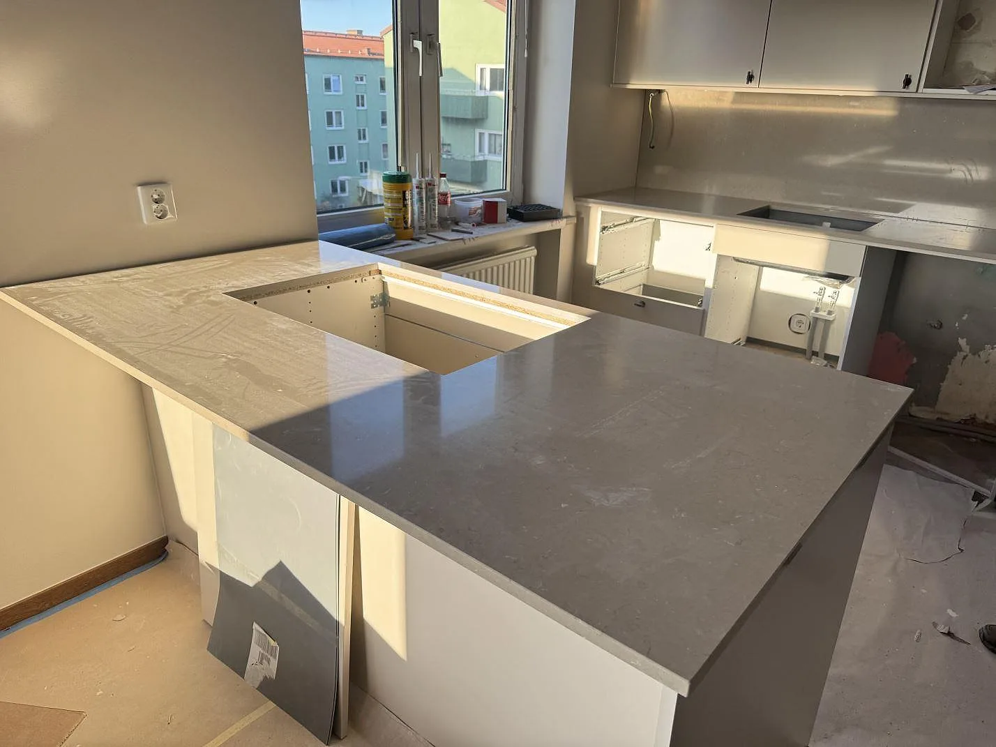 Køkkenbordplade i grå Silestone Coral Clay, poleret kvartskomposit, med køkkenø, förberedd öppning og stænkplade i Malmö.