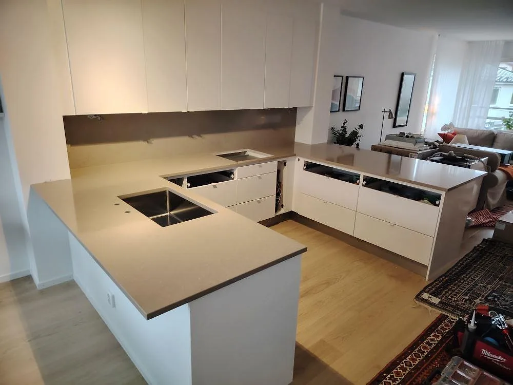 Køkkenbordplade i poleret Silestone Coral Clay, komposit, med U-formad arbetsyta og stænkplade i ett køkken i Sollentuna.