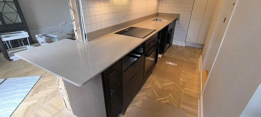 Køkkenbordplade i poleret Silestone Coral Clay komposit, 20 mm, med infälld kogeplade og lavt stænkplade i ett køkken i Stockholm.