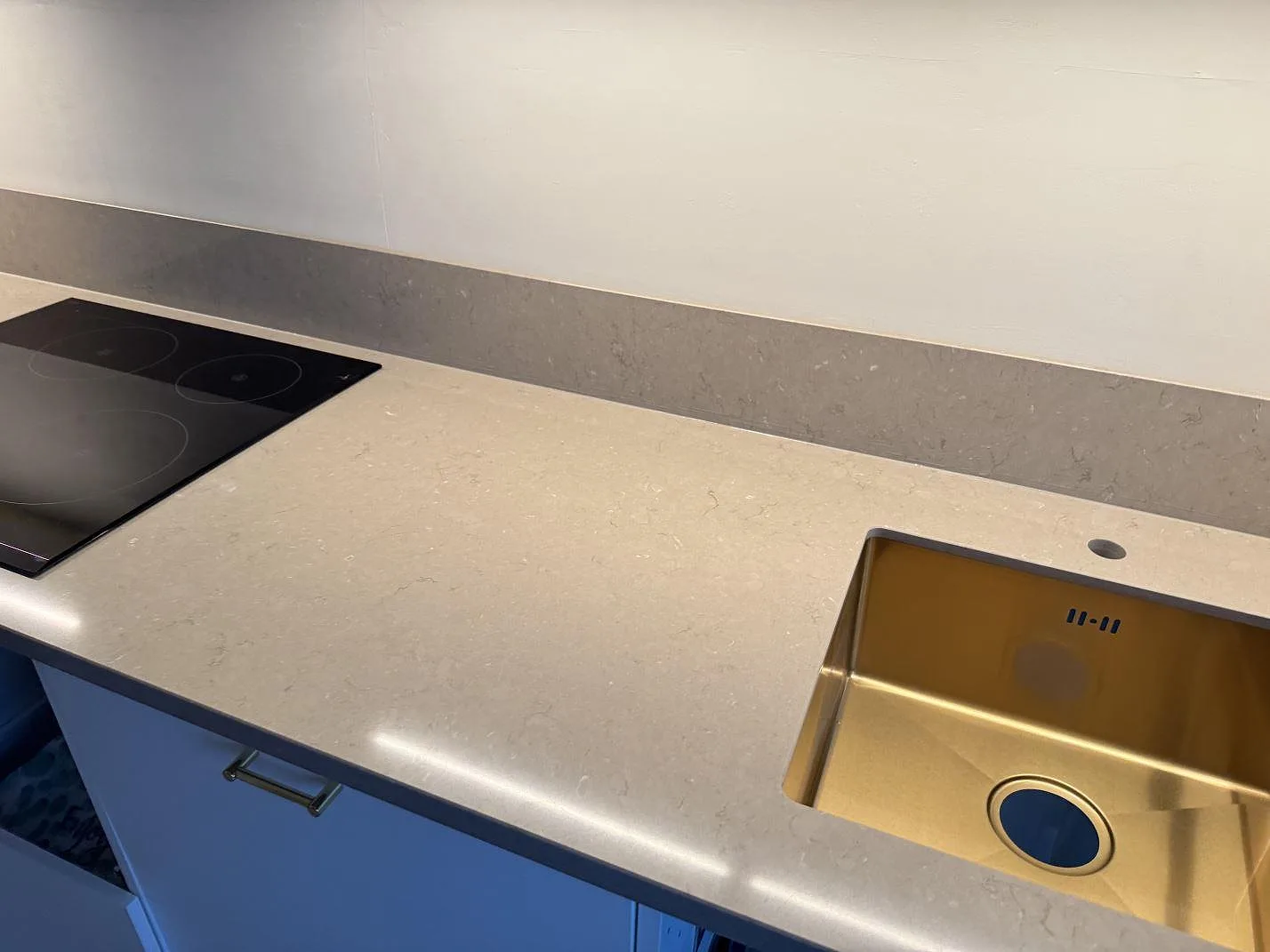 Køkkenbordplade i poleret Silestone Coral Clay, beigegrå komposit, med vask, kogeplade og låg stänkkant i ett køkken i Svedala.