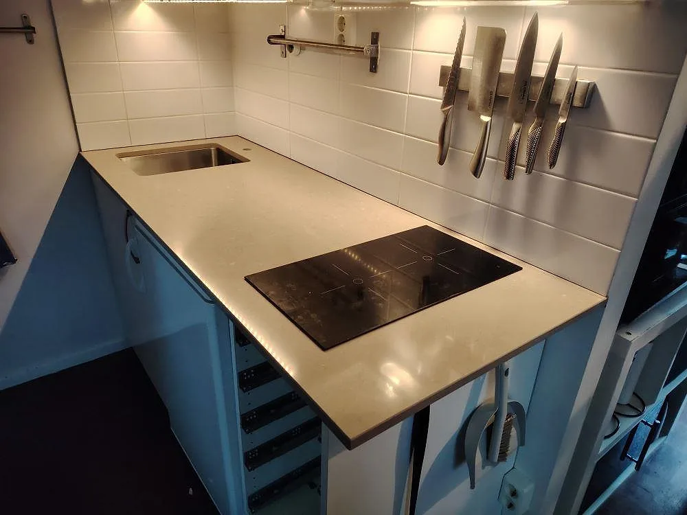 Poleret køkkenbordplade i Silestone Coral Clay, kvartskomposit, med rostfri vask og kogeplade i ett køkken med vitt kakel i Täby.