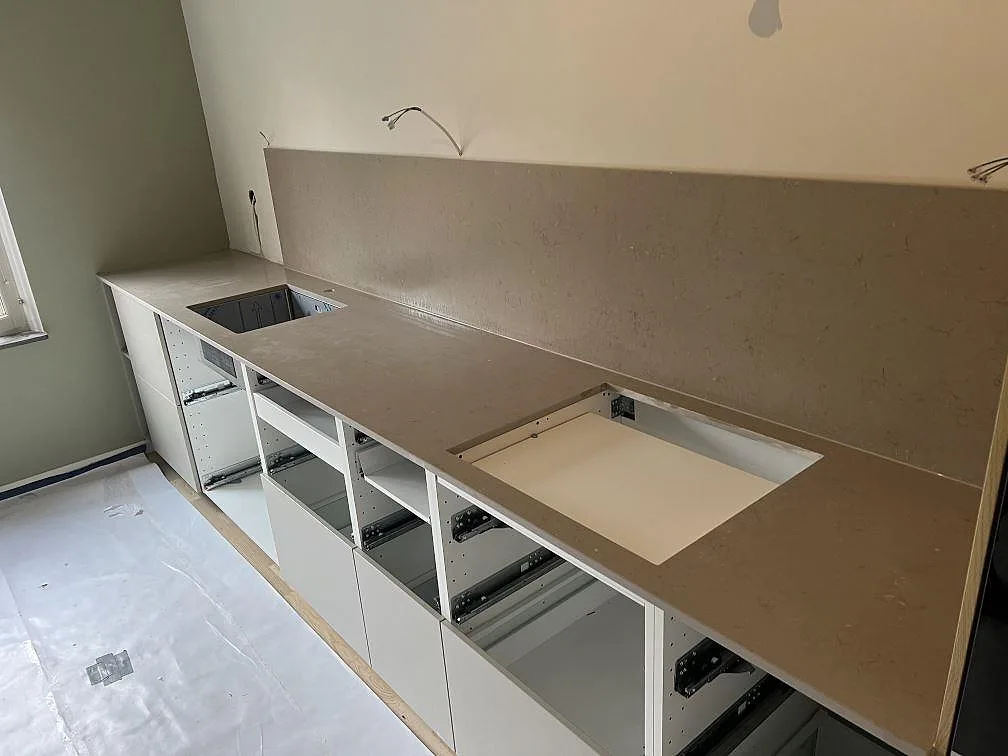 Køkkenbordplade i Silestone Coral Clay, mat komposit i Mocka, med stænkplade og udskæringer i ett køkken under montering i Tyresö.
