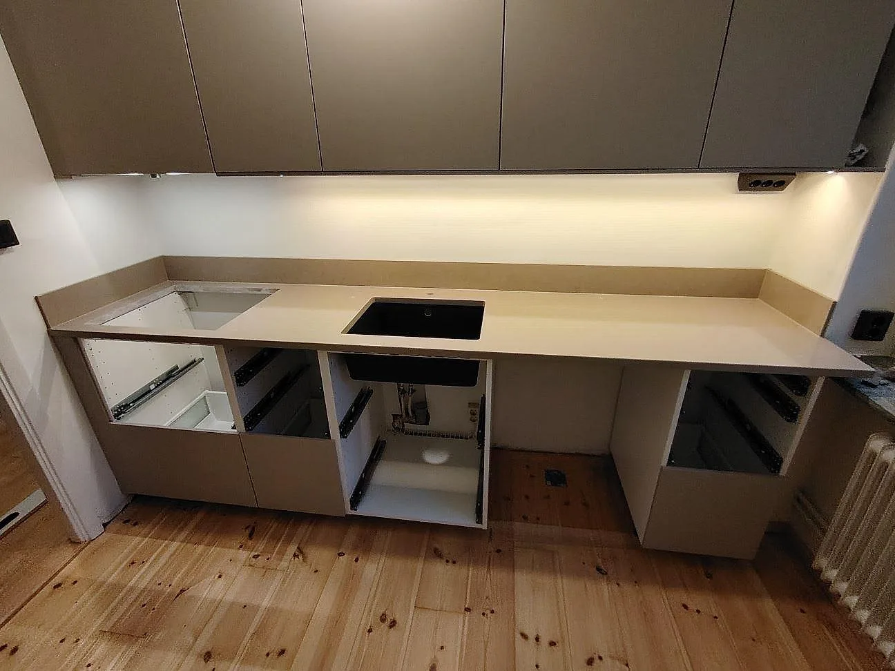 Køkkenbordplade i Silestone Coral Clay, poleret kvartskomposit, med underlimmad vask, hällurtag og uppvikt stänkkant i ett køkken i Uppsala.