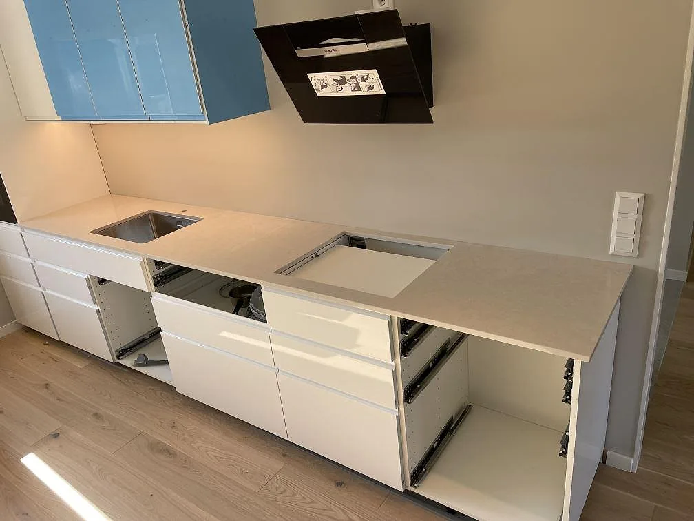 Køkkenbordplade i lys poleret Silestone Desert Silver med udtag for vask og kogeplade i ett køkken under montering i Ljungsbro.