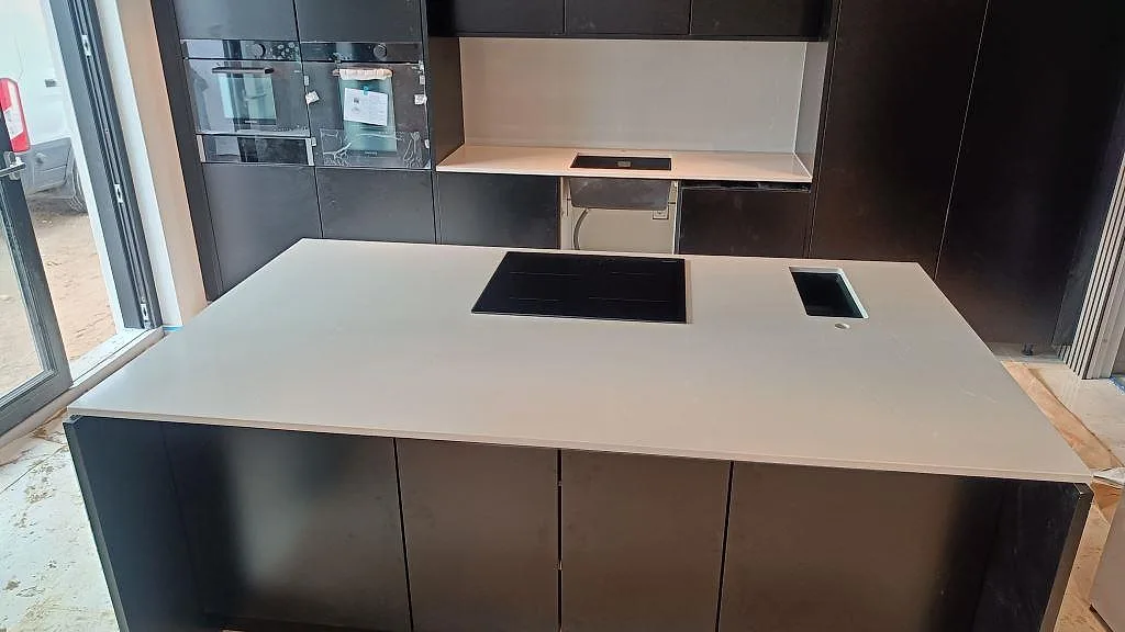 Køkkenbordplade i grå Silestone Desert Silver, poleret, på en køkkenø med infälld induktionshäll og underlimmad vask i ett køkken i Malmö.
