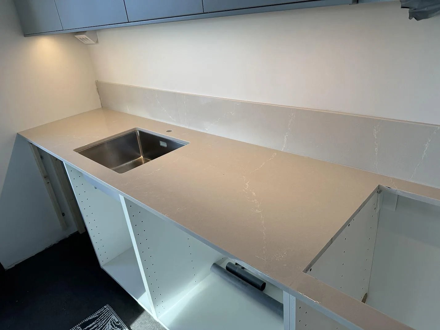 Køkkenbordplade i poleret Silestone Desert Silver med matchande stænkplade og rostfri vask i ett køkken i Malmö.