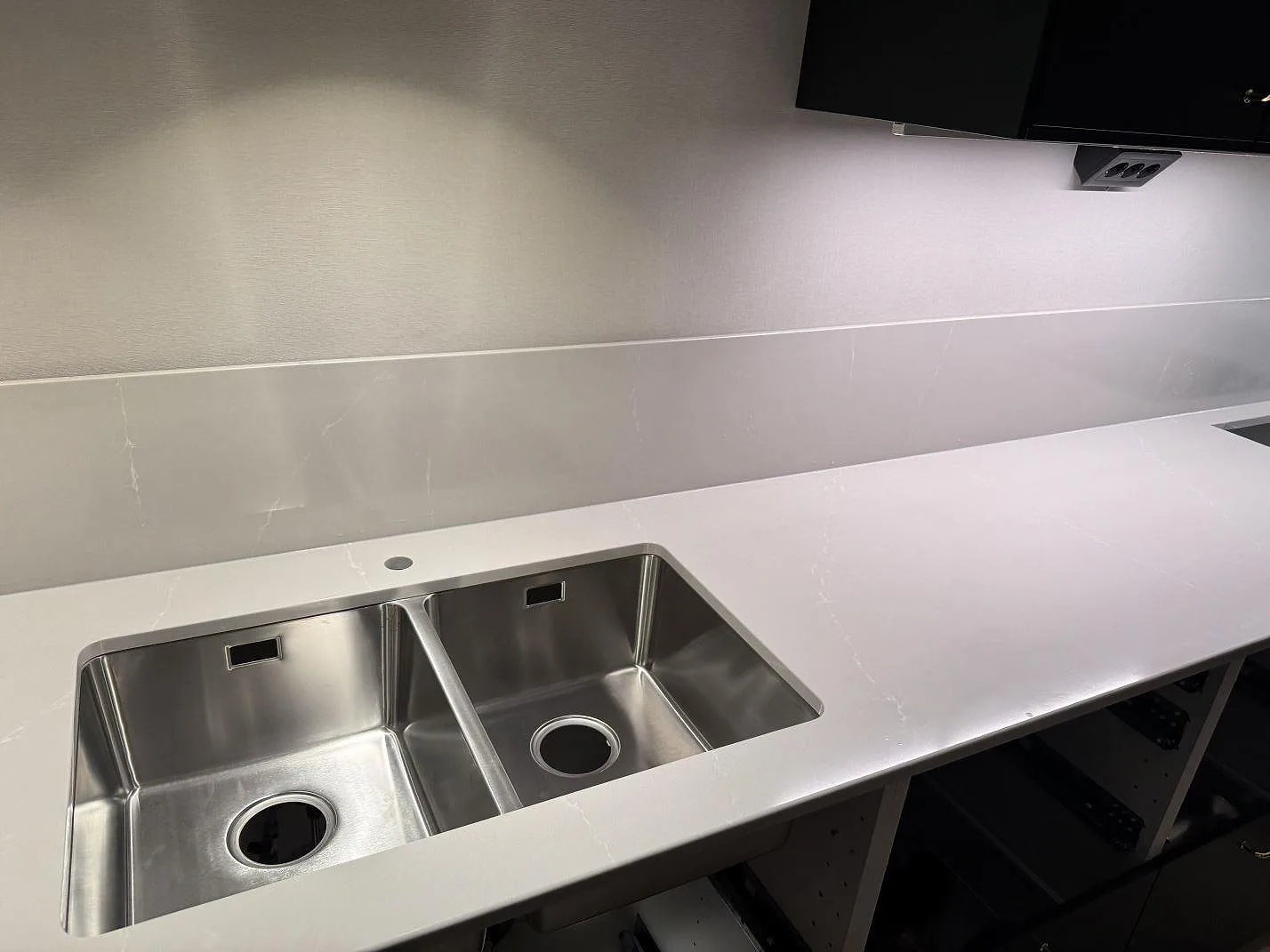Poleret køkkenbordplade i Silestone Desert Silver, kvartskomposit, med rostfri dubbelho og låg stänkkant i ett køkken i Ödåkra.