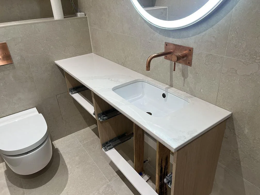 Badrumsbänkskiva i hvid kvartskomposit, Silestone Eternal Calacatta Gold, poleret, med underlimmat vitt tvättställ i Huddinge.