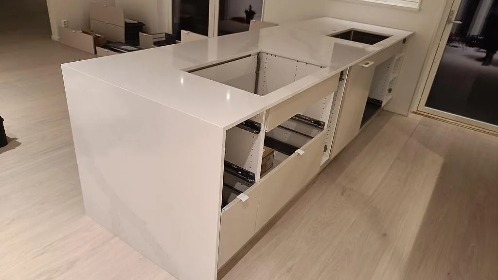 Køkkenbordplade i poleret Silestone Eternal Calacatta Gold med lys åretegning, rektangulära udskæring og nedvikt sida i ett køkken i Onsala.