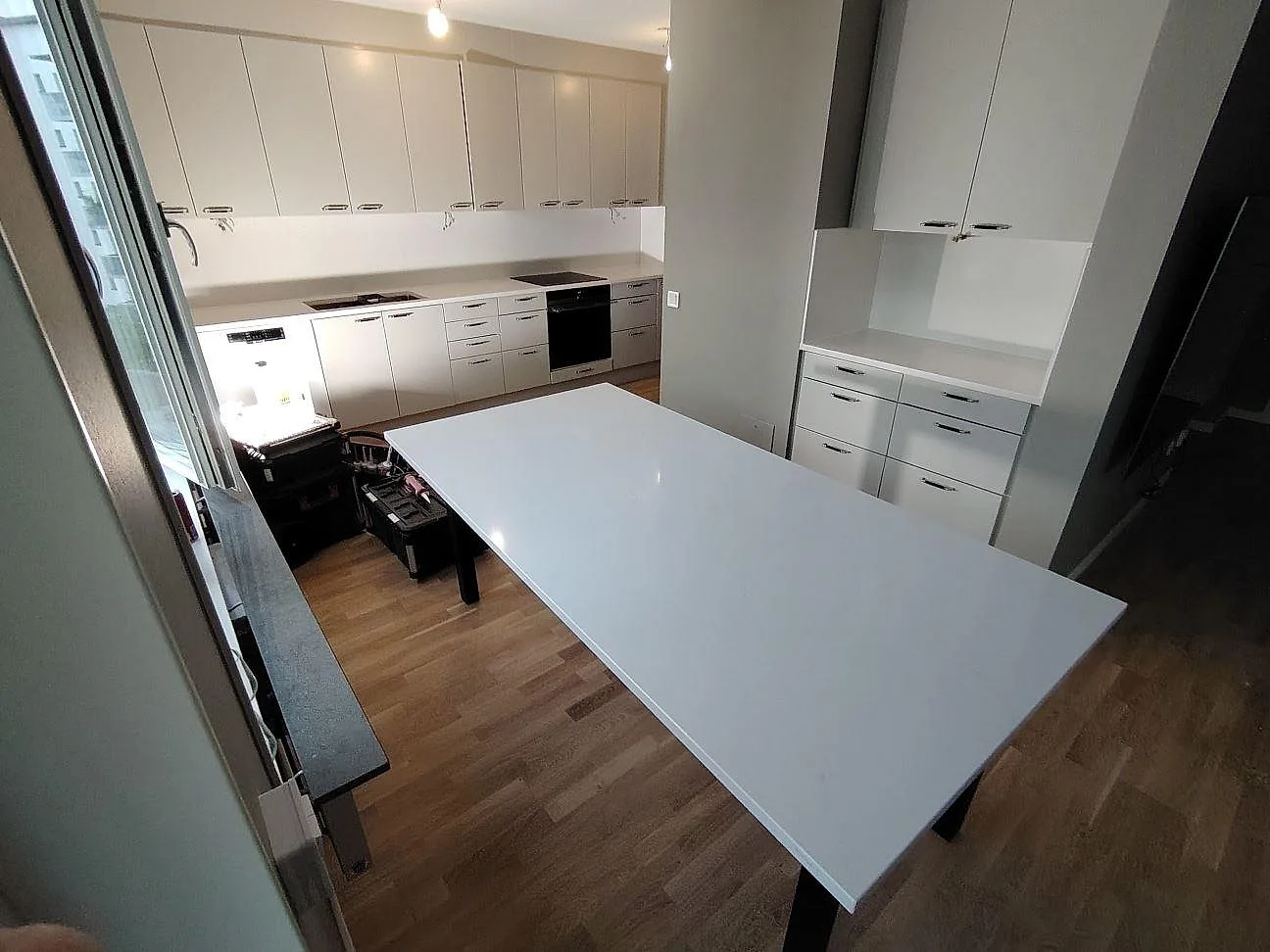 Stor poleret skivyta i Silestone Eternal Statuario komposit foran väggbänk og stænkplade i ett køkken under montering i Frösunda.