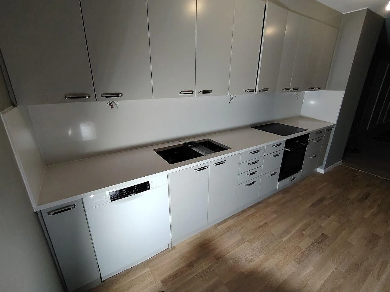 Poleret køkkenbordplade i hvid Silestone Eternal Statuario komposit med synlig vask, kogeplade og stænkplade i ett køkken i Frösunda.