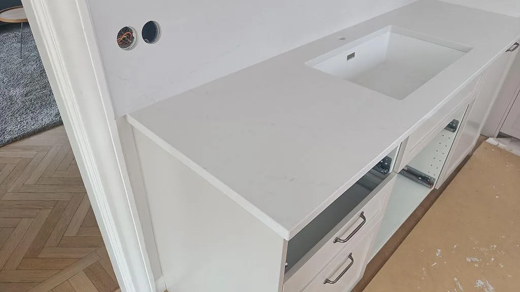 Køkkenbordplade i hvid Silestone Eternal Statuario, poleret, med vask og lys åretegning i ett køkken under montering i Limhamn.