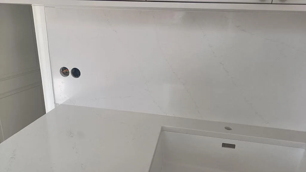 Närbild på hvid Silestone Eternal Statuario, poleret, med vask, väggskiva og grå åretegning i køkken i Limhamn.