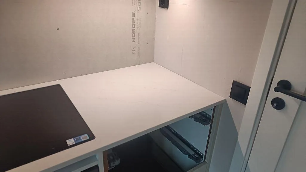 Hörnparti med kogeplade og Bordplade i poleret Silestone Eternal Statuario over öppna köksstommar i Varberg.