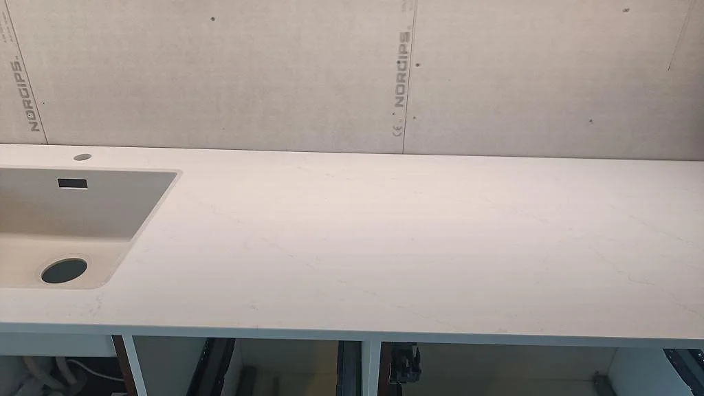 Lang køkkenbordplade i poleret Silestone Eternal Statuario med vask til venstre og öppen skab i Varberg.