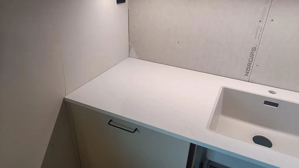 Bordplade i poleret Silestone Eternal Statuario med vask og lys väggskiva under montering i Varberg.