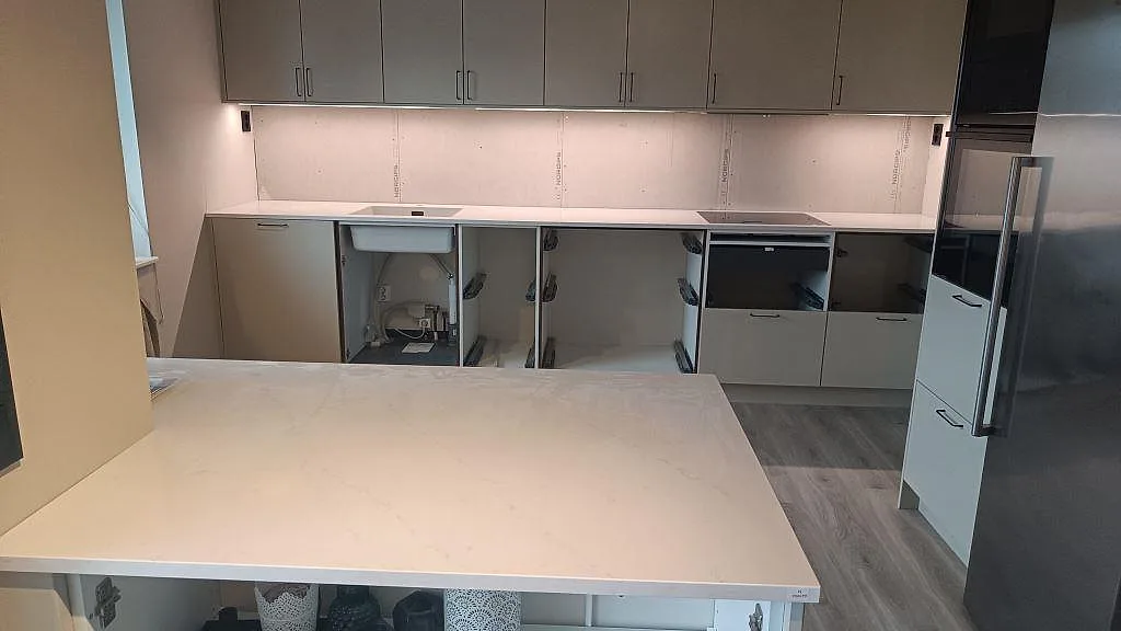 Køkkenbordplade i poleret Silestone Eternal Statuario med lys marmorering i ett køkken under montering i Varberg.