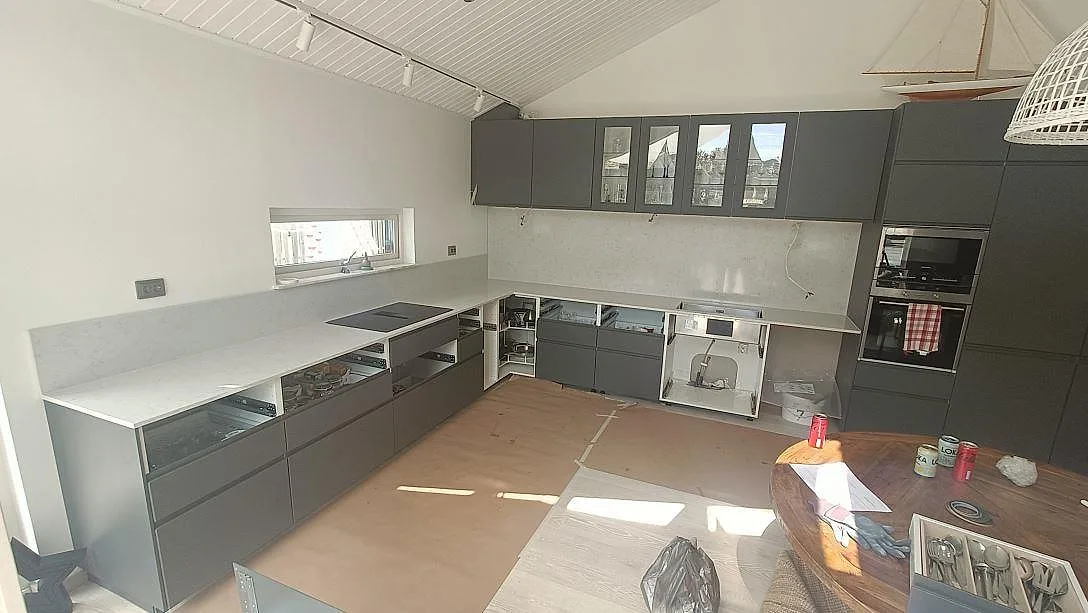 Køkkenbordplade i lys Silestone Lagoon, poleret, monteret i ett L-format køkken i Höllviken med infälld induktionshäll under installation.