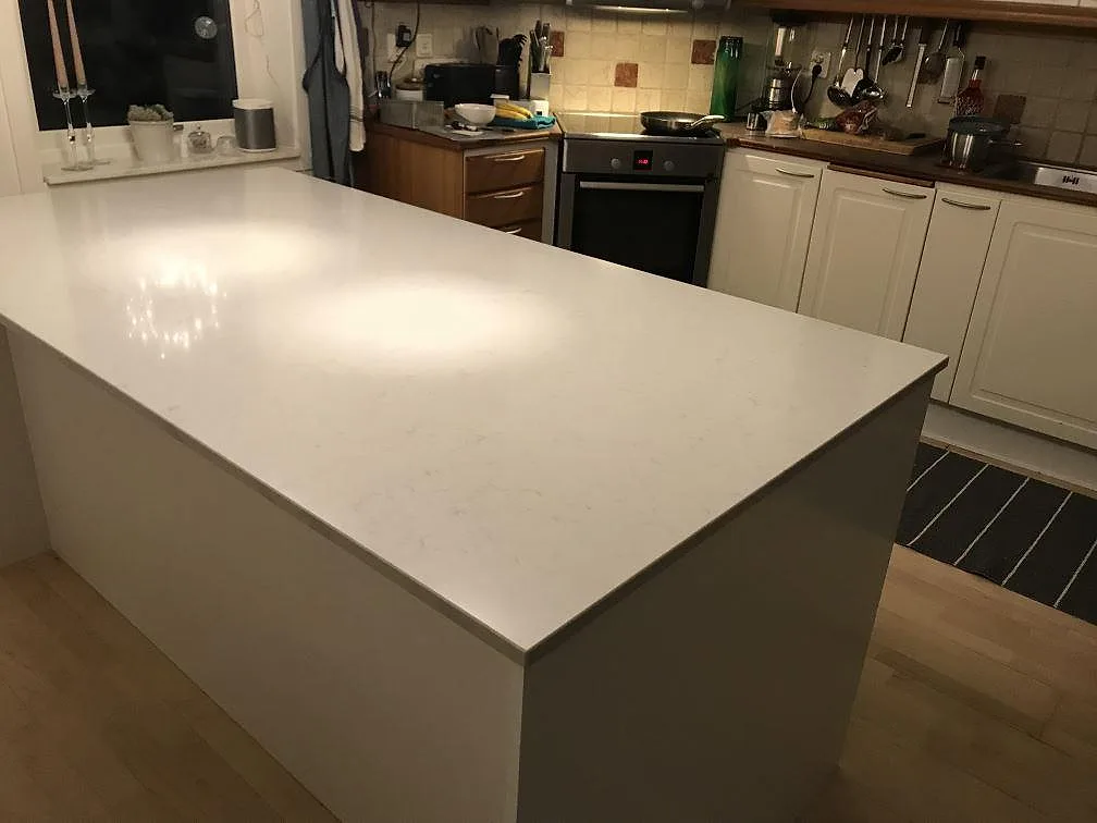 Køkkenbordplade i hvid Silestone Lagoon, poleret kvartskomposit, på en køkkenø i ett køkken i Pixbo.