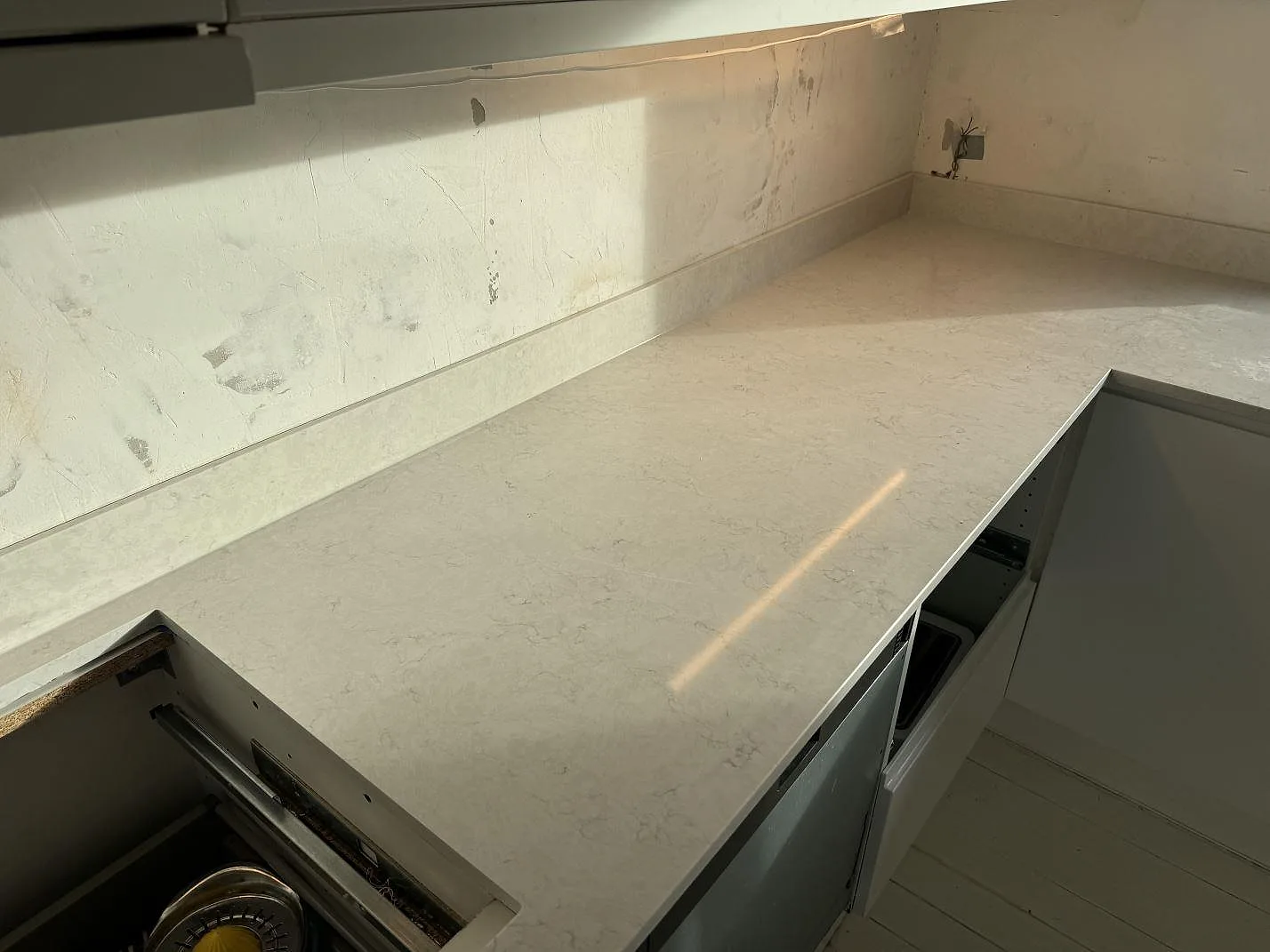 Køkkenbordplade i poleret Silestone Lagoon med matchande stænkplade og lys grå åretegning i ett køkken i Pixbo.