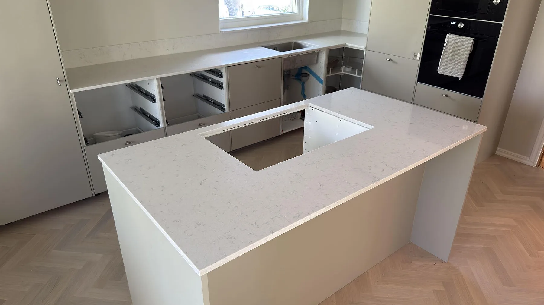 Køkkenbordplade og køkkenø i poleret Silestone Lagoon i ett køkken under montering på Värmdö.