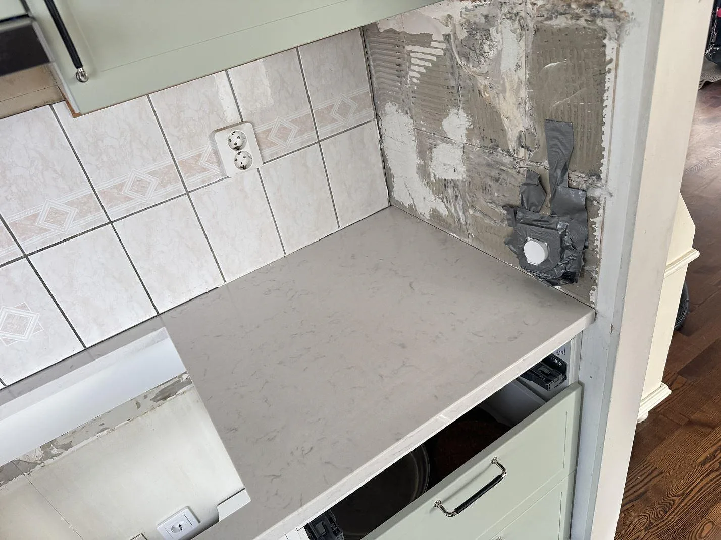 Poleret køkkenbordplade i Silestone Lagoon, 30 mm, med lys grå åretegning vid befintlig kakelvägg i ett køkken i Varberg.