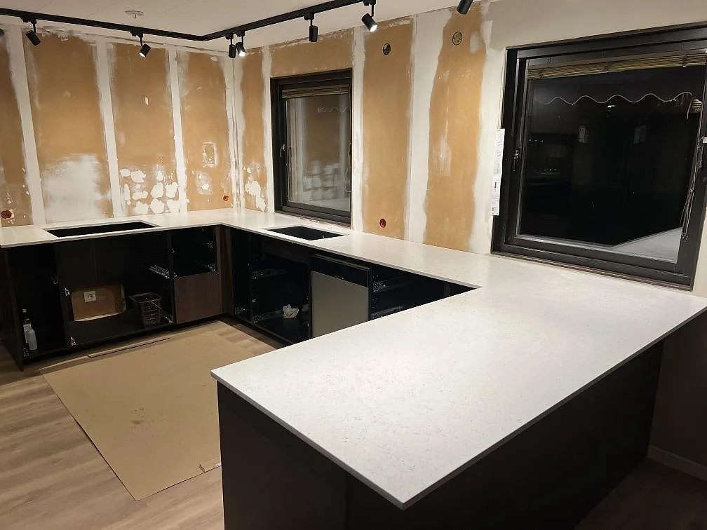 Køkkenbordplader i lys Silestone Lime Delight, mat Mocka, monterade rundt om køkkenø og vindue i ett køkken under renovering i Ludvika.