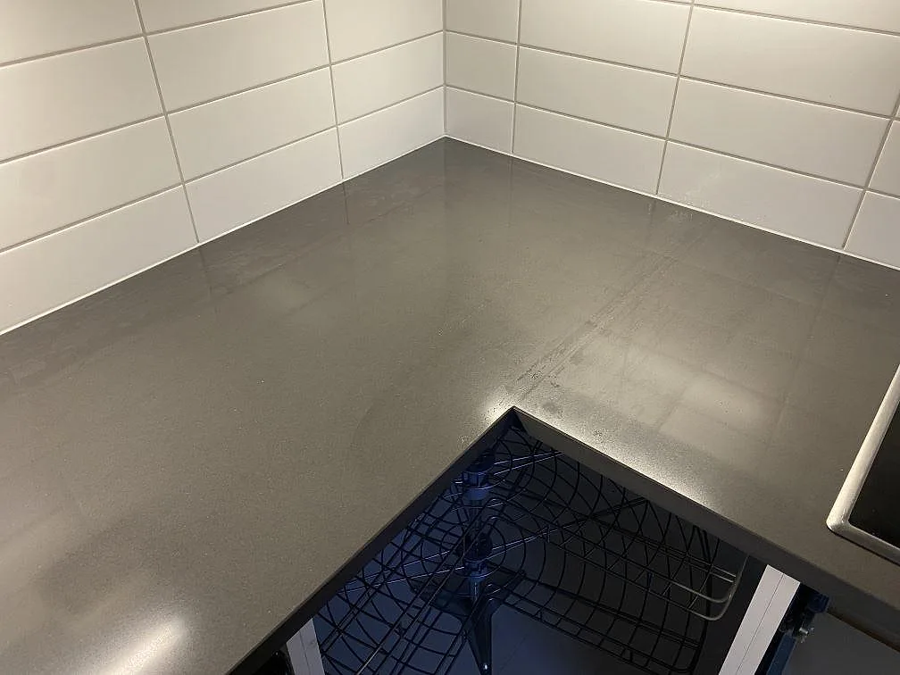 Køkkenbordplade i mörkgrå Silestone Marengo, poleret, monteret i hjørner mot vitt kakel i ett køkken i Falkenberg.