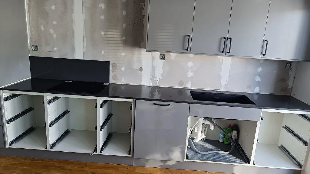 Køkkenbordplade i mörkt antracitgrå Silestone Marengo, poleret, med underlimmad kompositdiskho i ett køkken under montering i Löddeköpinge.