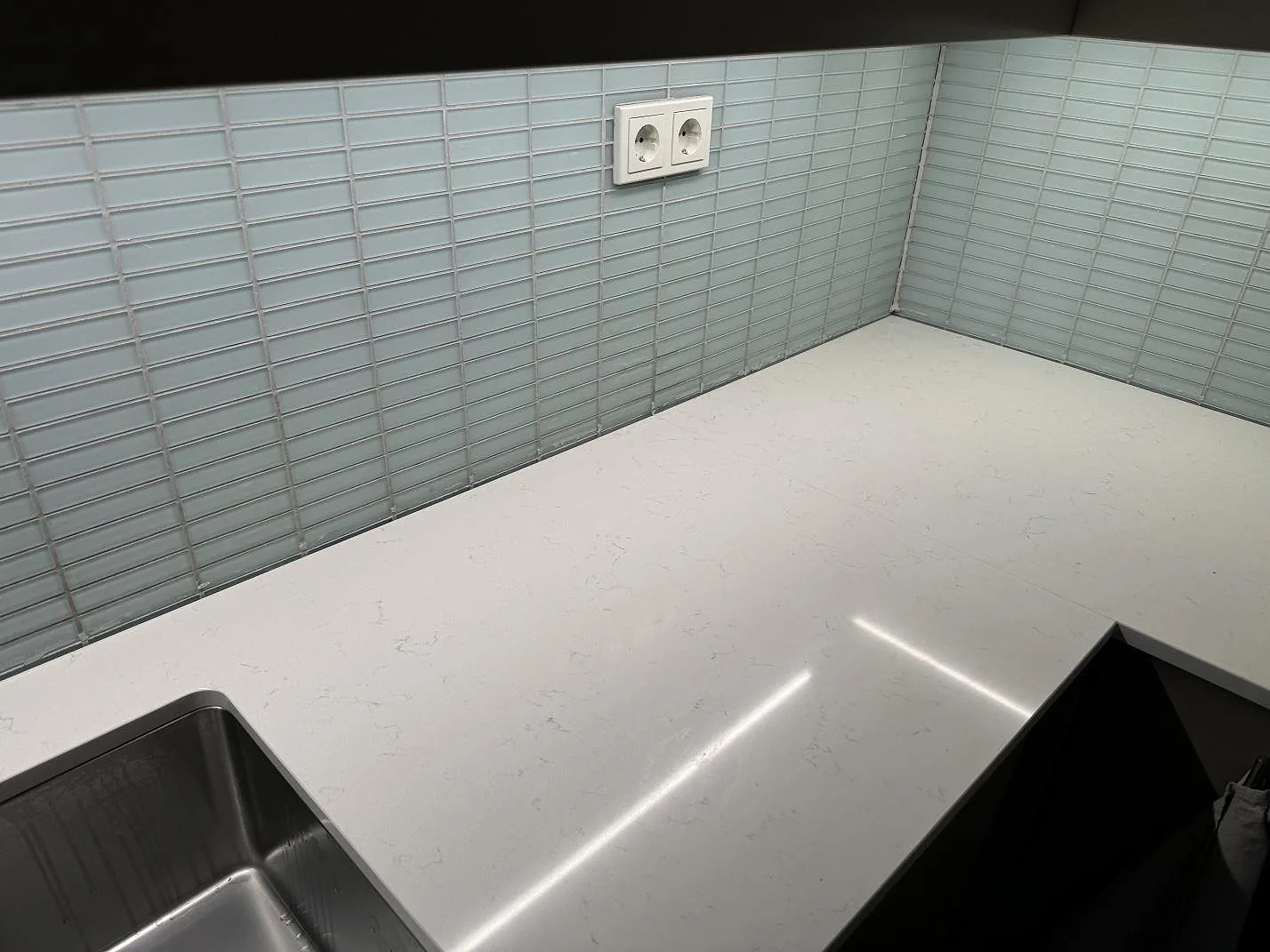 Køkkenbordplade i poleret Silestone Miami Vena kvartskomposit i ett L-format køkken i Malmö, med rostfri vask og lys kakelvägg.