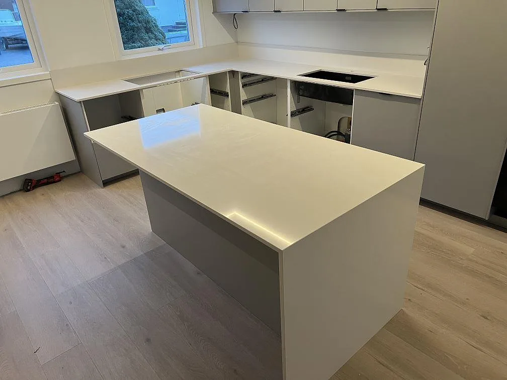 Køkkenbordplade og køkkenø i poleret hvid Silestone Miami White komposit med låg stänkkant i ett køkken i Örebro.