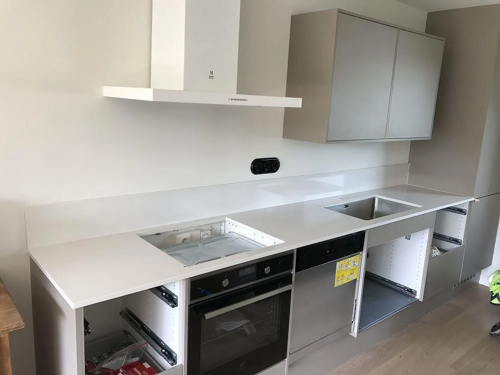 Køkkenbordplade i hvid Silestone Miami White, poleret, monteret längs en lang lige köksrad med underlimmad rostfri vask og öppen hultagning for hällen i ett køkken i Simrishamn.