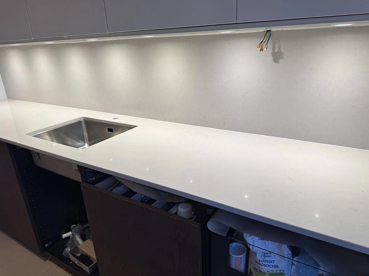 Lang køkkenbordplade i poleret Silestone Motion Grey med underlimmad rostfri vask og stænkplade i ett køkken i Lomma.