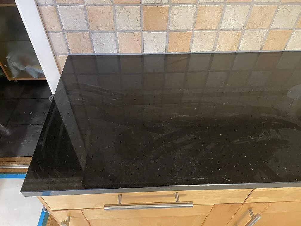 Køkkenbordplade i sort Silestone Negro Tebas, poleret, monteret mot lyse träluckor i ett køkken i Åkarp.