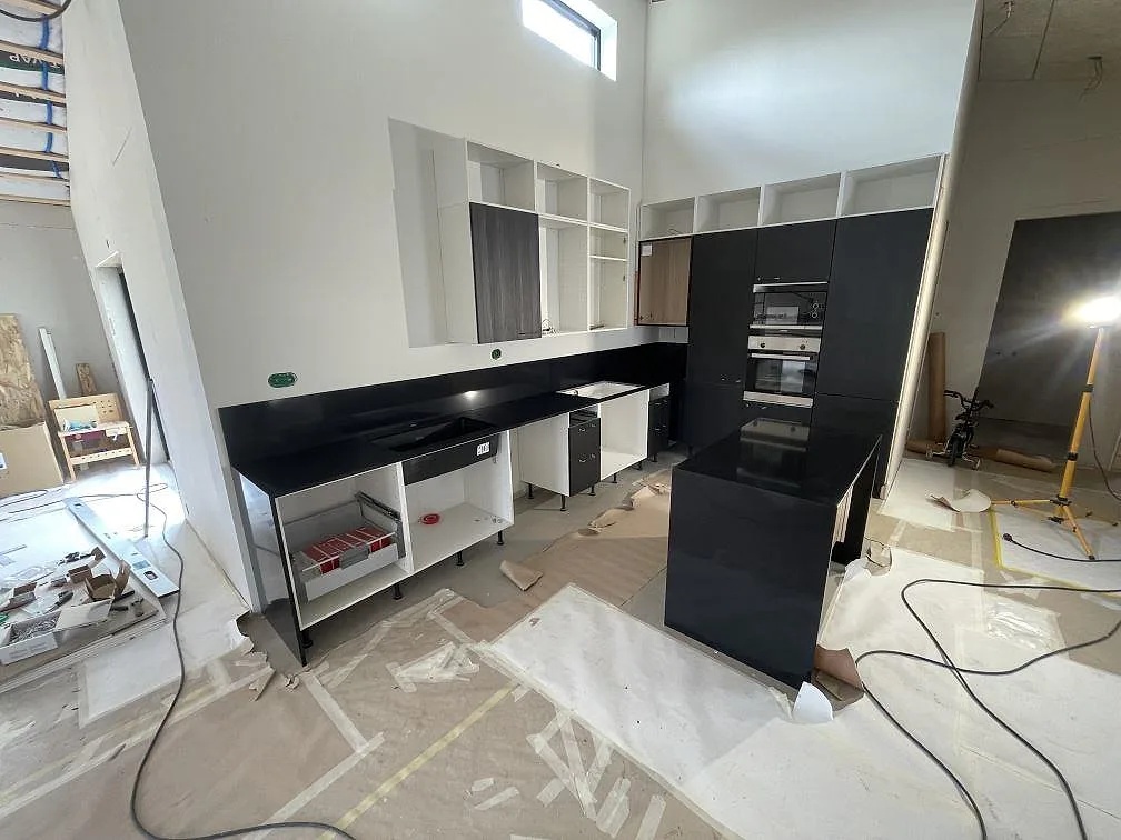 Køkkenbordplade i mørk Silestone Night Tebas, poleret högglans, med køkkenø og bänkrad mot væg i ett køkken under montering i Skövde.
