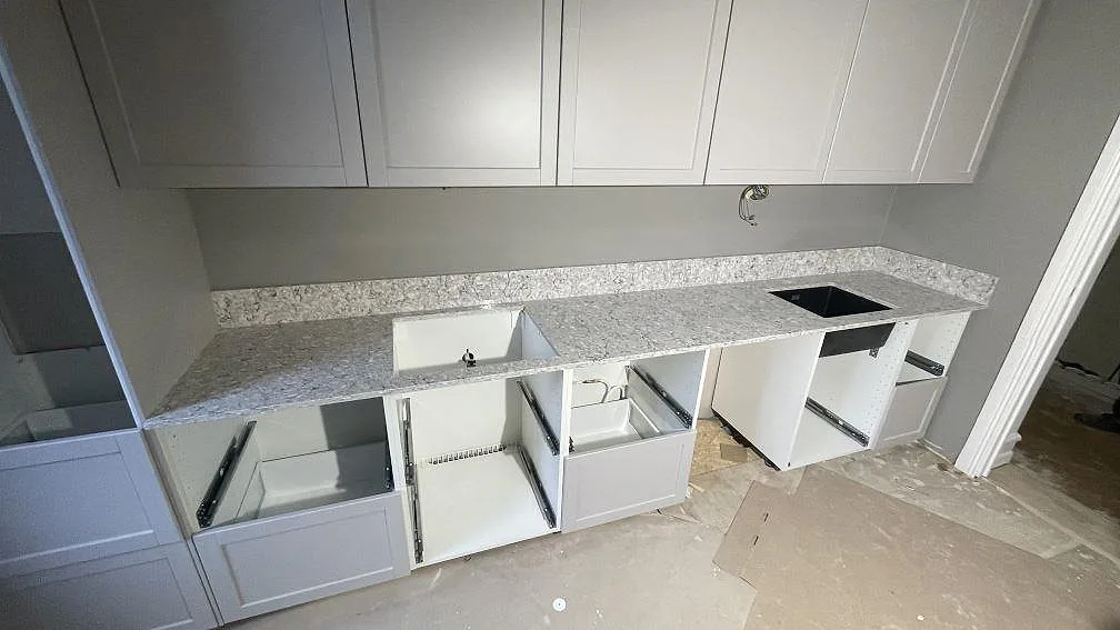 Køkkenbordplade i grå Silestone Pietra, poleret kvartskomposit, med stänkkant, sort vask og hällöppning i ett køkken i Malmö.