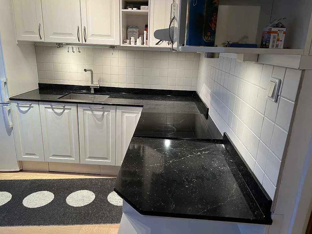 Køkkenbordplade i mørk Silestone Romantic Ash, poleret komposit, med vask, kogeplade og hvid kakelvägg i Bromma.