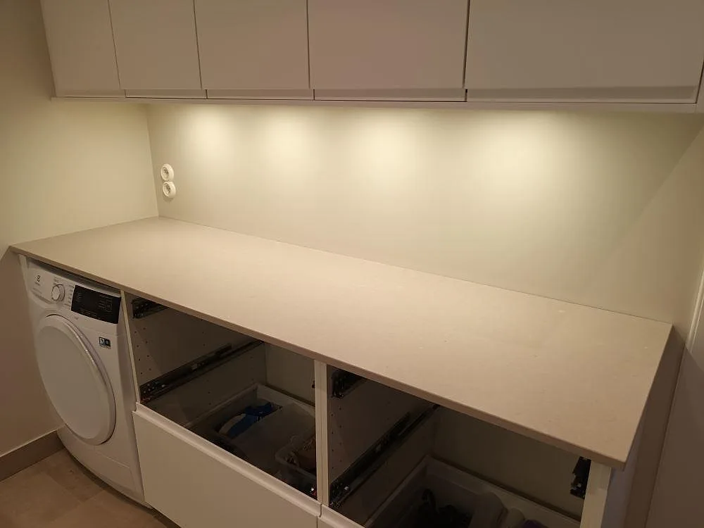 Køkkenbordplade i beige Silestone Royal Reef med Mocka-overflade, monteret i en tvättstuga i Falun under installation med öppna skabe.